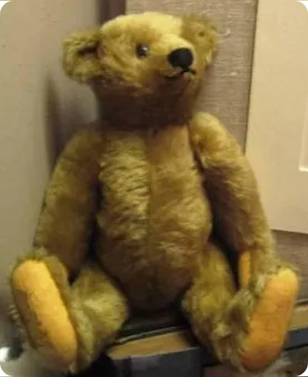 Brown plush teddy bear replica sitting in the corner